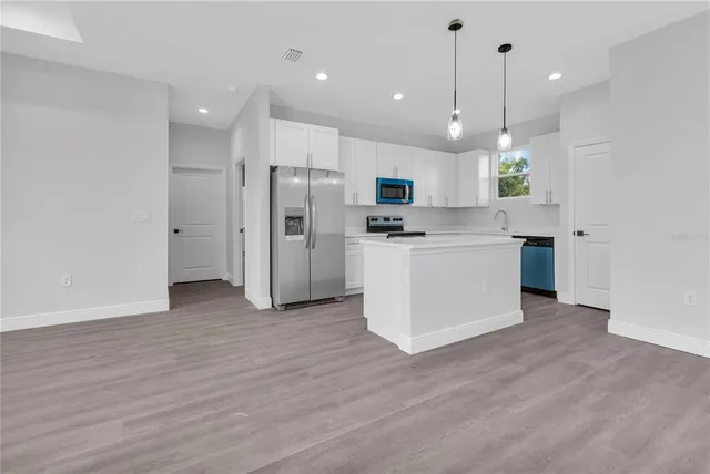 a view of kitchen with stainless steel appliances granite countertop cabinets and wooden floor