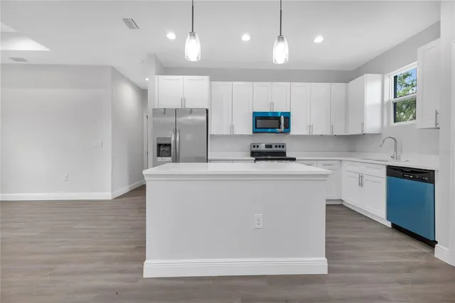 a kitchen with kitchen island white cabinets and stainless steel appliances
