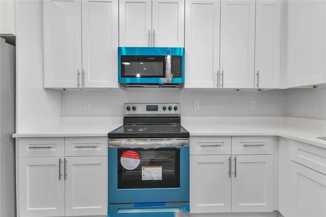 a kitchen with white cabinets and a stove with wooden floor