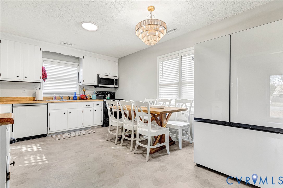 6377 Sledds Lake Road Mechanicsville, VA 23111 - Photo 5 of 15 a kitchen with stainless steel appliances granite countertop a white table chairs and a refrigerator