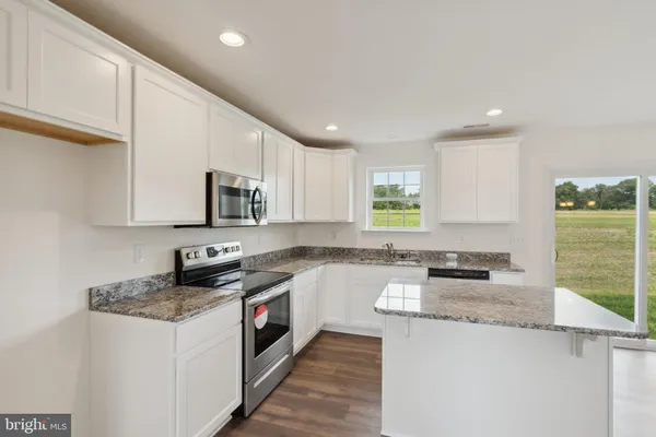a kitchen with granite countertop a sink a stove a counter space and cabinets
