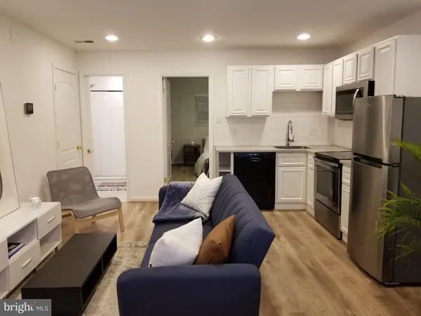 a living room with stainless steel appliances kitchen island granite countertop a couch and a refrigerator