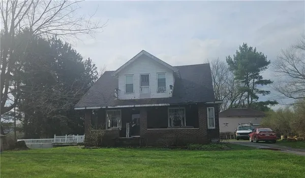 a front view of a house with a garden and trees