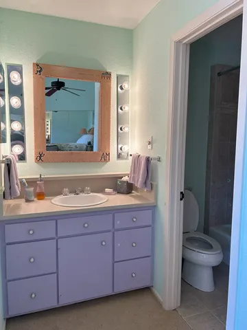 a bathroom with a granite countertop toilet a sink and a mirror