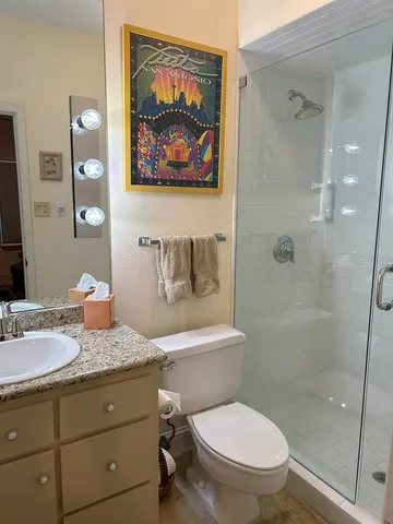 a bathroom with a granite countertop toilet a sink and glass door