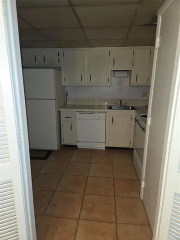 a kitchen with granite countertop white cabinets and refrigerator