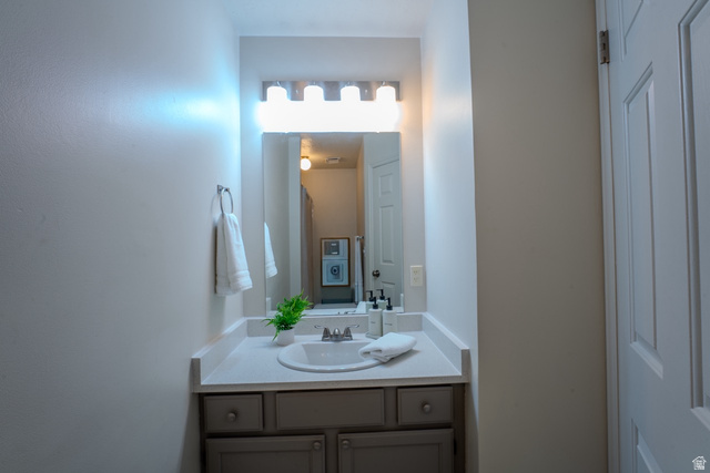11957 Noelle Road Sandy, UT 84092 - Photo 26 of 38 Bathroom vanity featuring a light countertop with an integrated sink, a large wall-mounted mirror, and a contemporary four-bulb light fixture