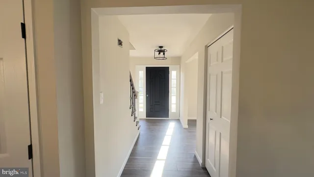 a view of a hallway with wooden floor and a bathroom