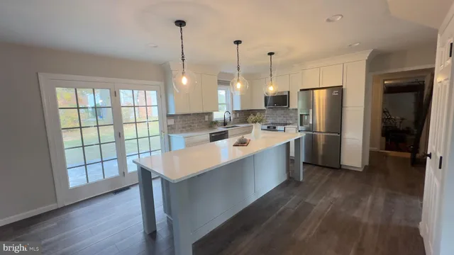 a large kitchen with stainless steel appliances a refrigerator a sink dishwasher a oven and wooden floor