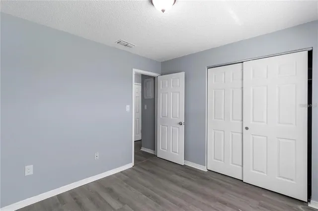a view of an empty room with closet and a window