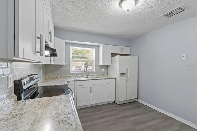 a kitchen with stainless steel appliances granite countertop a sink stove and refrigerator