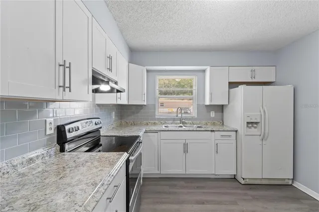 a kitchen with stainless steel appliances granite countertop a sink stove and refrigerator