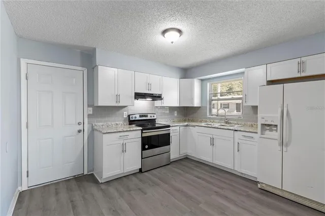 a kitchen with granite countertop white cabinets and white appliances