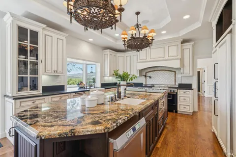 a kitchen with stainless steel appliances granite countertop a sink a stove top oven a counter space and cabinets