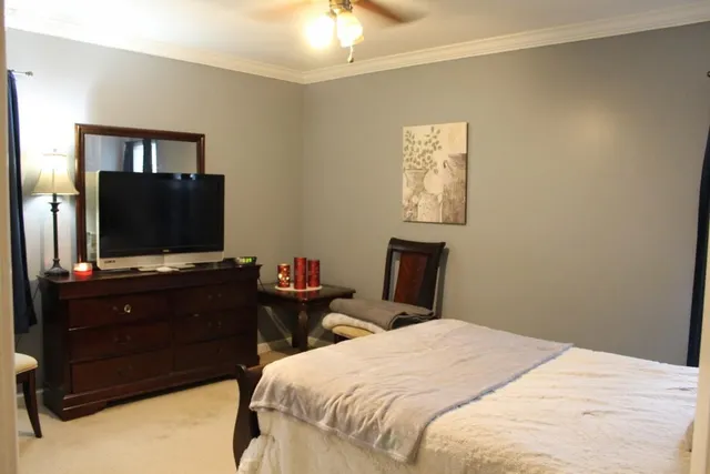 a bedroom with a bed and a flat tv screen on dresser