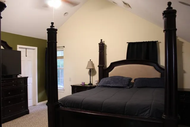 a bedroom with a bed and a flat tv screen on the dresser