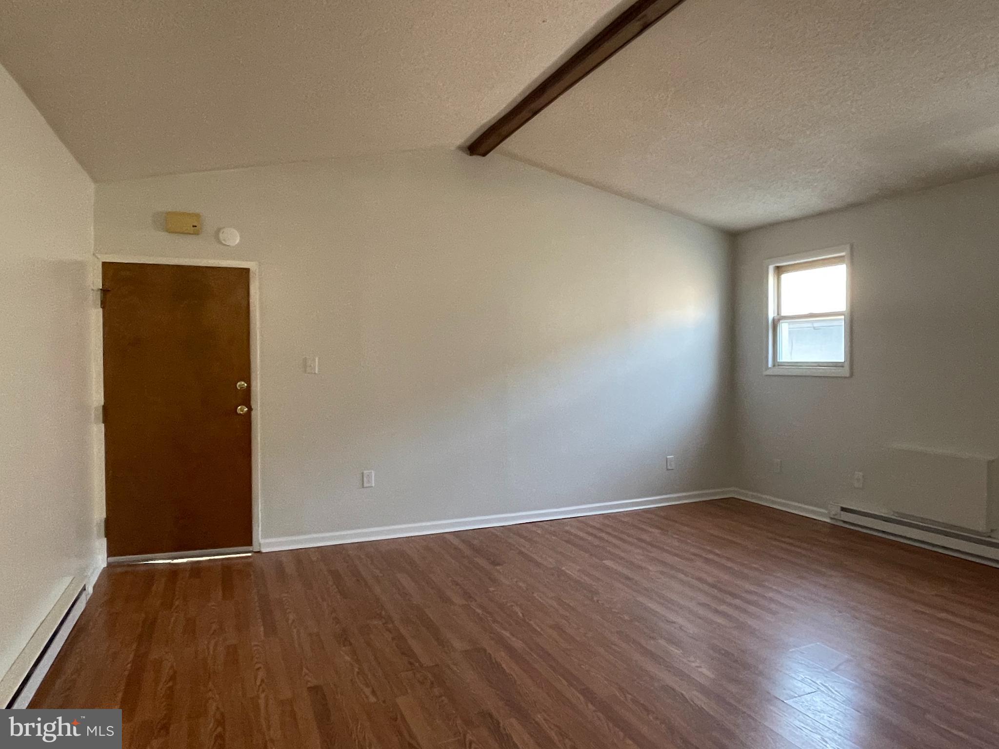317 Bridge Street, Unit 2 Phoenixville, PA 19460 - Photo 5 of 12 an empty room with wooden floor and windows