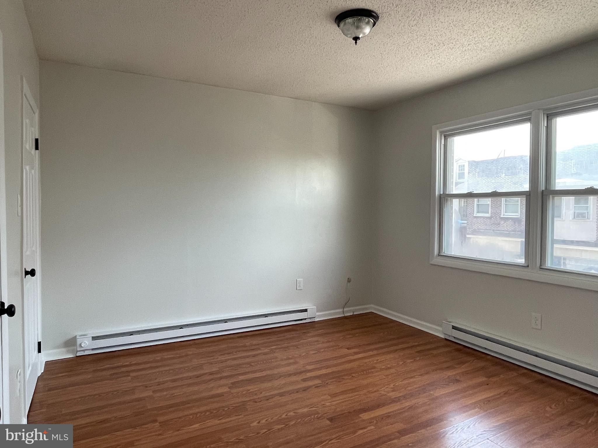 317 Bridge Street, Unit 2 Phoenixville, PA 19460 - Photo 10 of 12 an empty room with wooden floor and windows