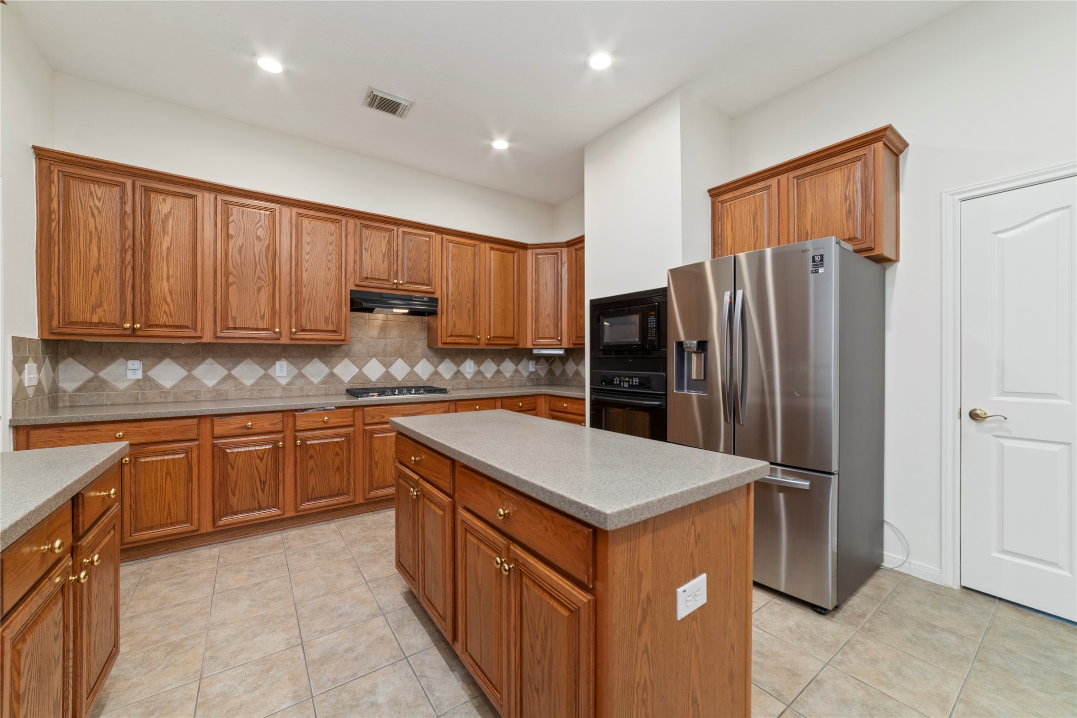 11108 Dawson Road Pearland, TX 77584 - Photo 30 of 43 a kitchen with stainless steel appliances a refrigerator and wooden cabinets