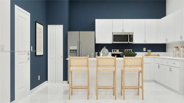 a kitchen with stainless steel appliances a refrigerator sink stove and white cabinets