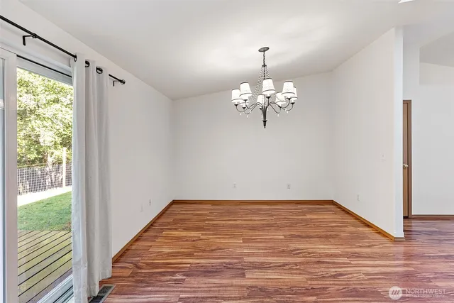 a view of a hallway with wooden floor and a chandelier