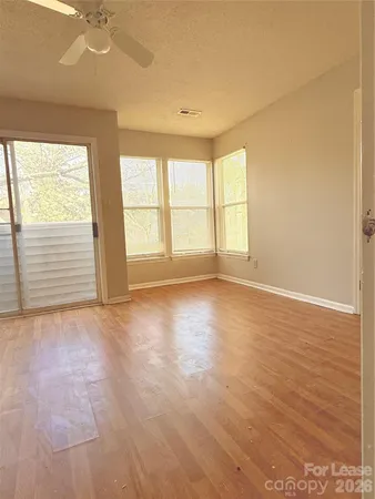 an empty room with wooden floor and windows