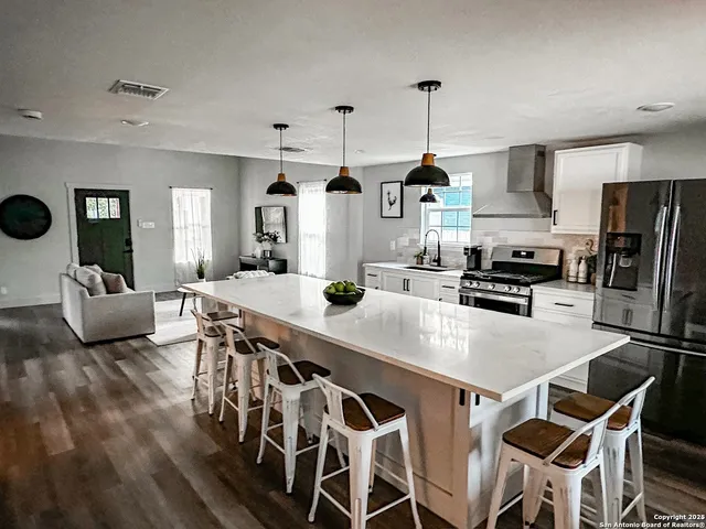 a kitchen with stainless steel appliances kitchen island granite countertop a table chairs and a refrigerator