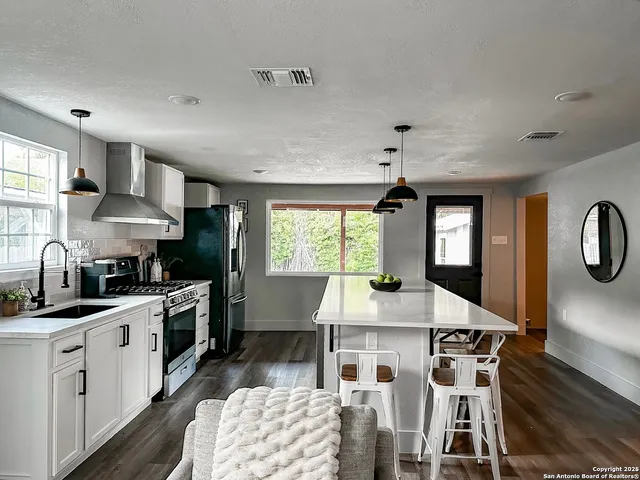 a kitchen with stainless steel appliances granite countertop a stove a sink dishwasher a microwave oven with white cabinets and wooden floor