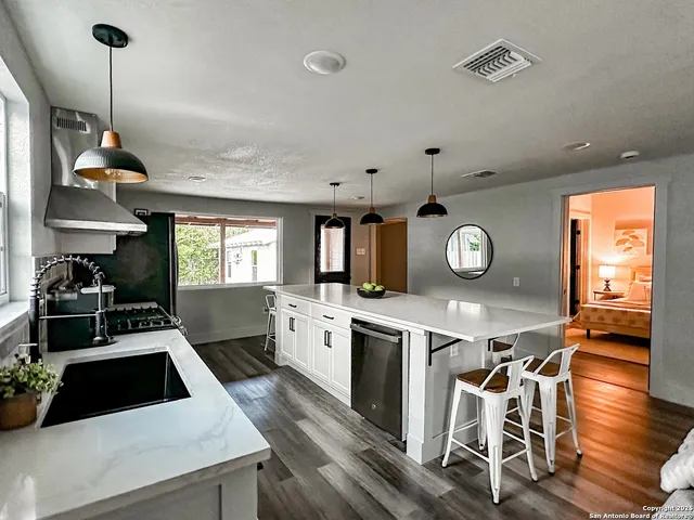 a kitchen with a stove a refrigerator a sink dishwasher a dining table and chairs with wooden floor