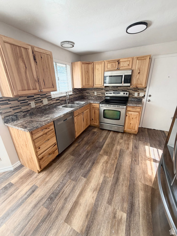9571 David Street, Unit UPSTR Sandy, UT 84070 - Photo 3 of 13 Kitchen featuring wood-finish cabinetry, stainless steel appliances, a mosaic tile backsplash, and wood-finish flooring
