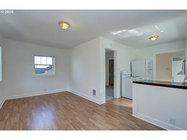 a view of an empty room with wooden floor and windows