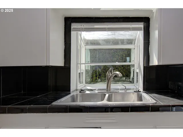 a living room with stainless steel appliances kitchen island a sink a stove and cabinets