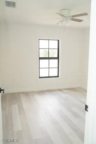 an empty room with a window and a ceiling fan