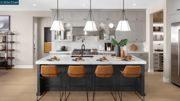 a kitchen with stainless steel appliances a sink a stove a refrigerator and chairs