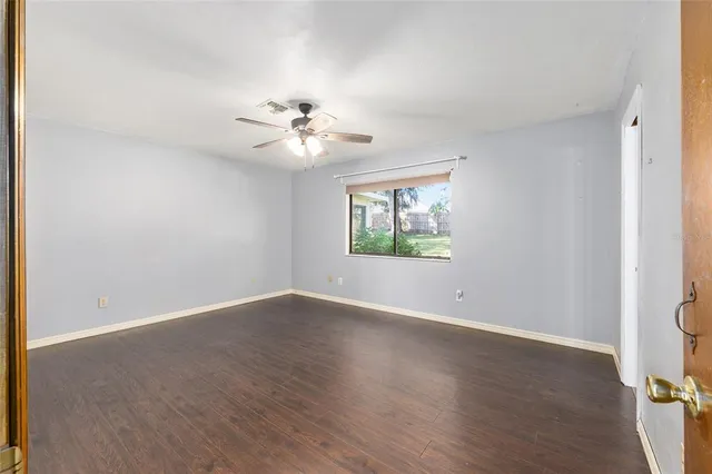 a view of an empty room with a window and wooden floor