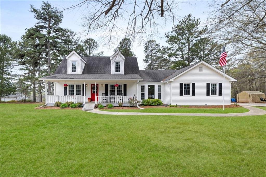 a view of a white house in front of a big yard with large trees