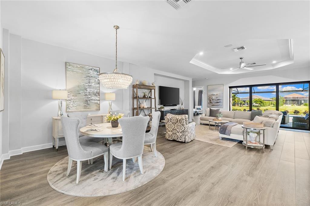 15345 Aprile Street Naples, FL 34114 - Photo 12 of 29 a dining room with furniture a chandelier and wooden floor