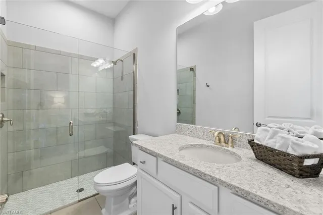 a bathroom with a granite countertop sink a toilet a mirror and shower