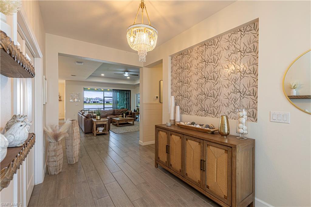 20278 Kingmont Drive Estero, FL 33928 - Photo 5 of 38 Hall with visible vents, an inviting chandelier, and wood finished floors