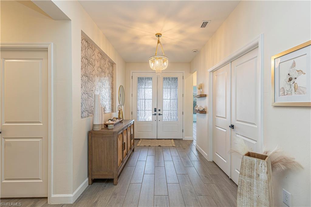 20278 Kingmont Drive Estero, FL 33928 - Photo 6 of 38 Entryway featuring baseboards, a chandelier, french doors, visible vents, and light wood finished floors