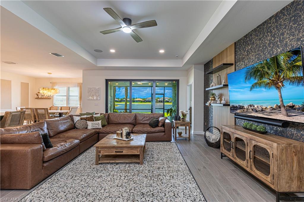 20278 Kingmont Drive Estero, FL 33928 - Photo 8 of 38 Living room with visible vents, a tray ceiling, recessed lighting, wood finished floors, and ceiling fan with notable chandelier