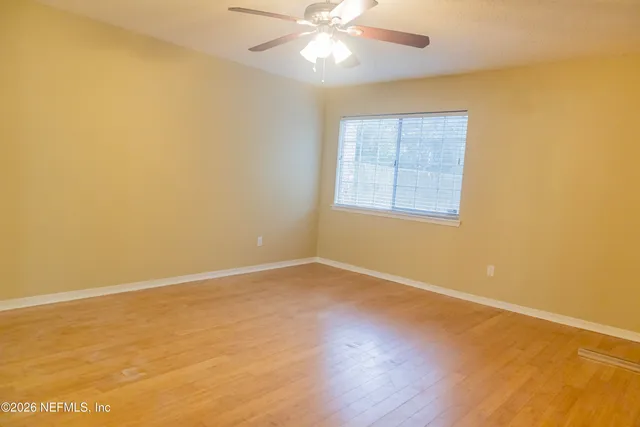 an empty room with a window and wooden floor