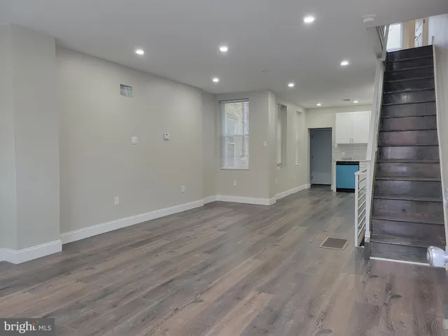 a view of an empty room with wooden floor and stairs