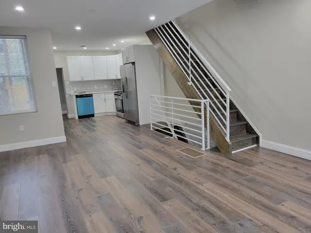 an empty room with wooden floor windows and staircase