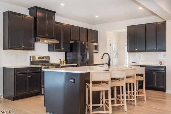 a kitchen with stainless steel appliances kitchen island granite countertop a stove refrigerator and cabinets