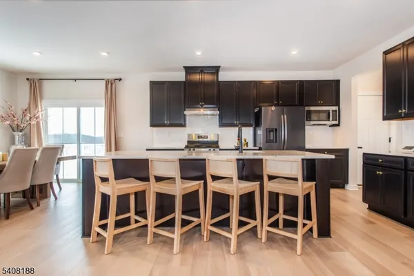 a kitchen with stainless steel appliances a dining table chairs refrigerator and microwave
