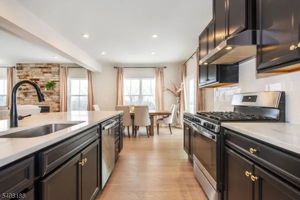 a kitchen with stainless steel appliances kitchen island granite countertop a table chairs sink and cabinets