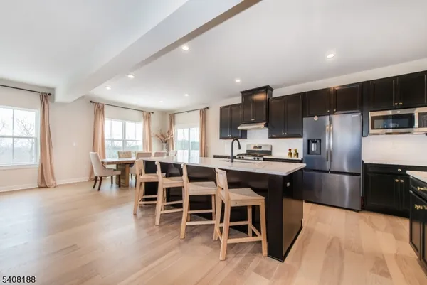 a kitchen with stainless steel appliances kitchen island granite countertop a table chairs sink and cabinets