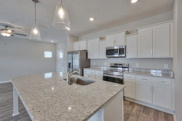 a kitchen with kitchen island a sink stainless steel appliances and white cabinets