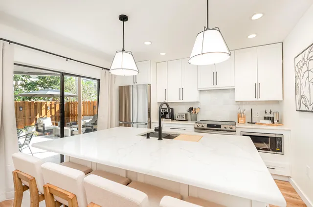 a kitchen with kitchen island a large counter top space a sink appliances and cabinets